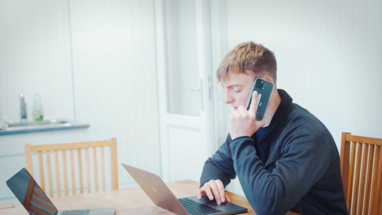 Vendsyssel Fjerkræslagteri - En mand der sidder foran en computer med en mobil telefon i øret